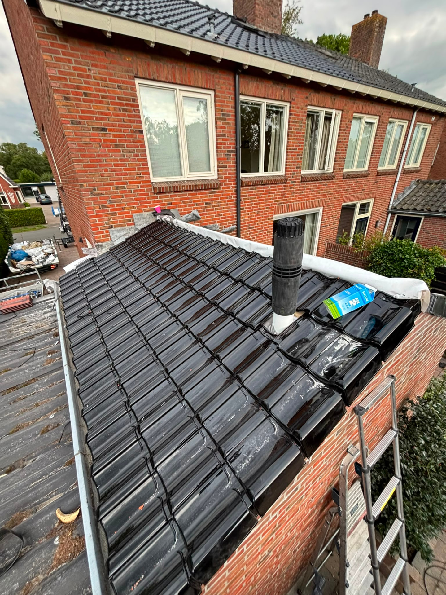 Dakreparatie aan een zwart geglazuurd pannendak