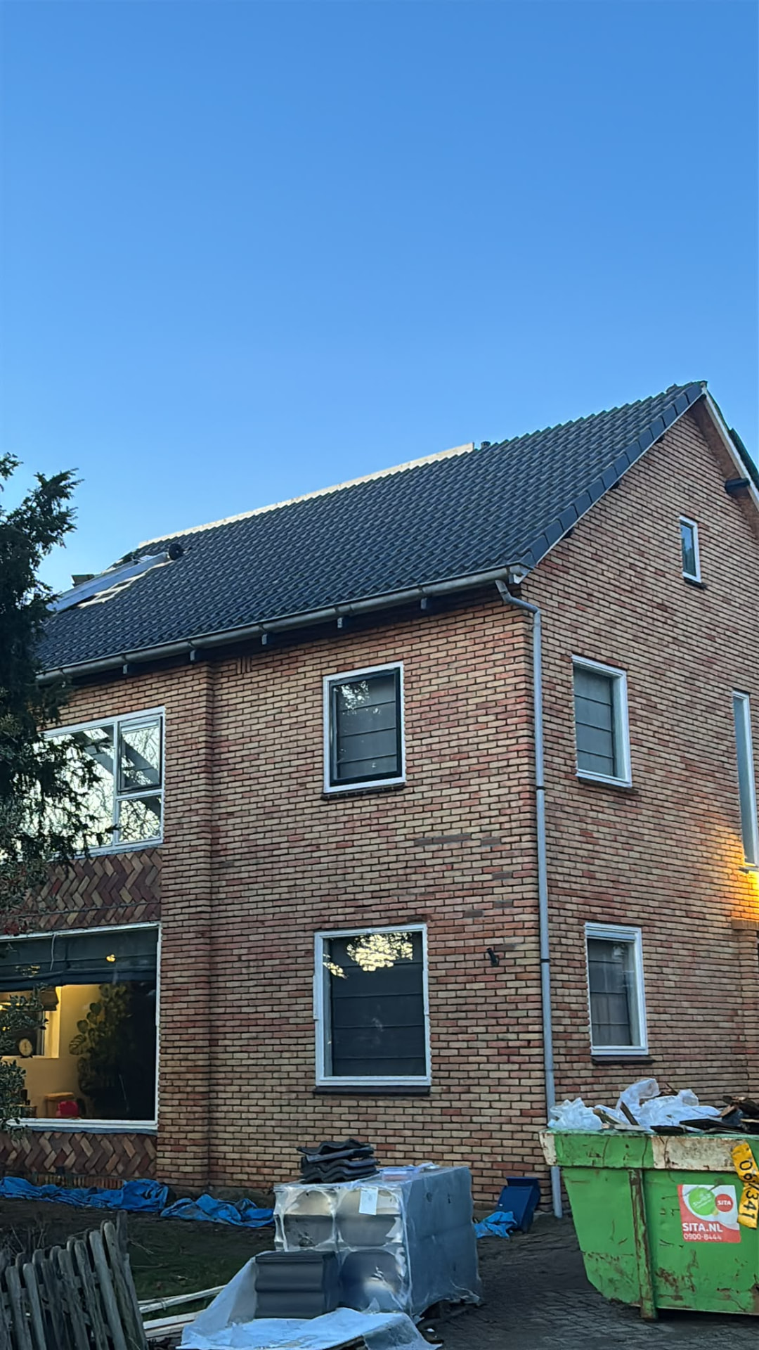 Bakstenen woning met een compleet nieuw gelegd donker pannendak