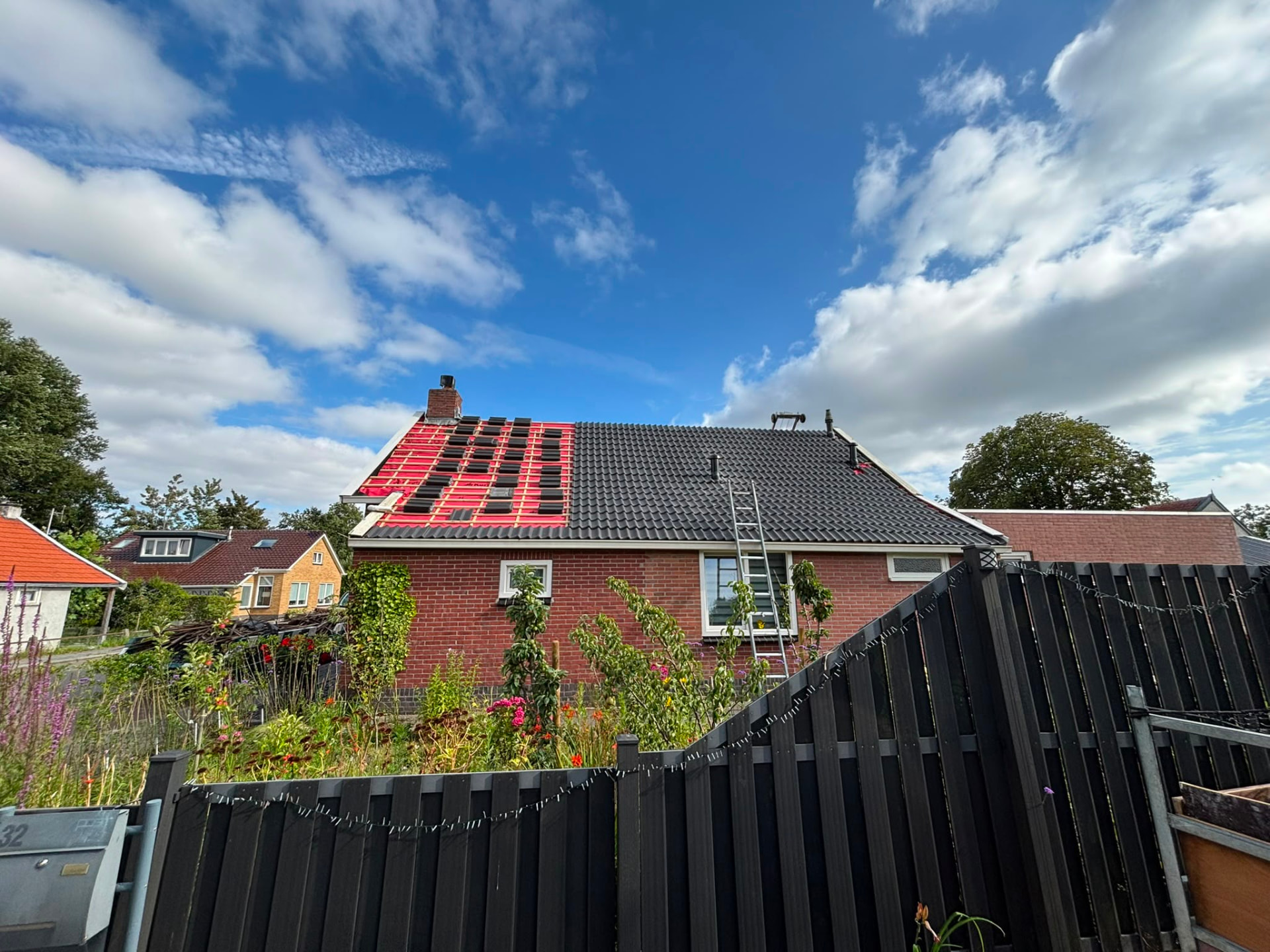 Dakrenovatie in uitvoering: helft nieuwe pannen, helft rood onderdak