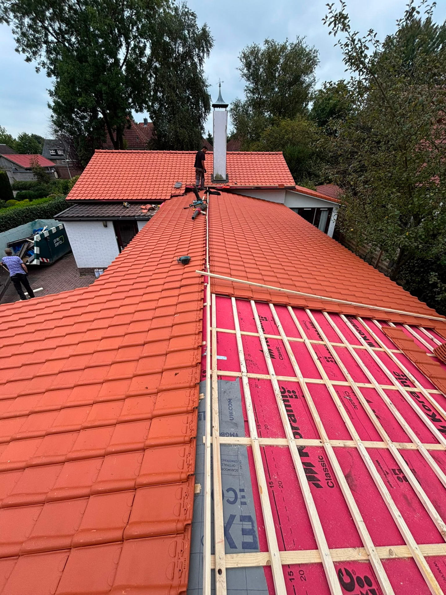Dakdekker van HR Dakconstructie voert een dakrenovatie uit met nieuwe rode dakpannen